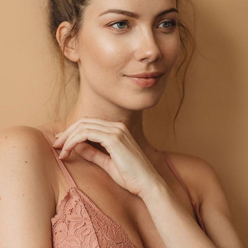 Woman with subtle smile against a neutral background.