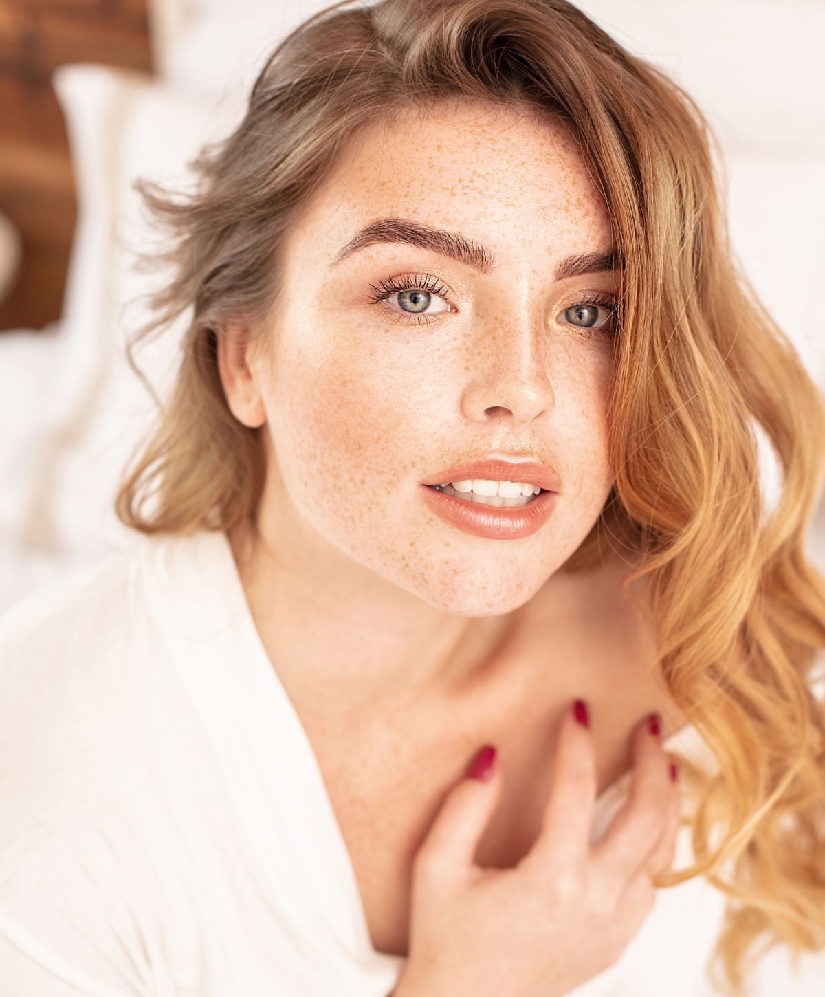 Smiling woman with freckles and wavy hair.
