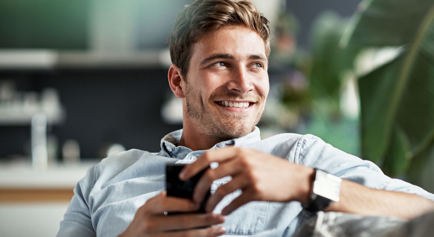 Young Denver men's non-surgical treatments model sitting casually indoors, shirtless.