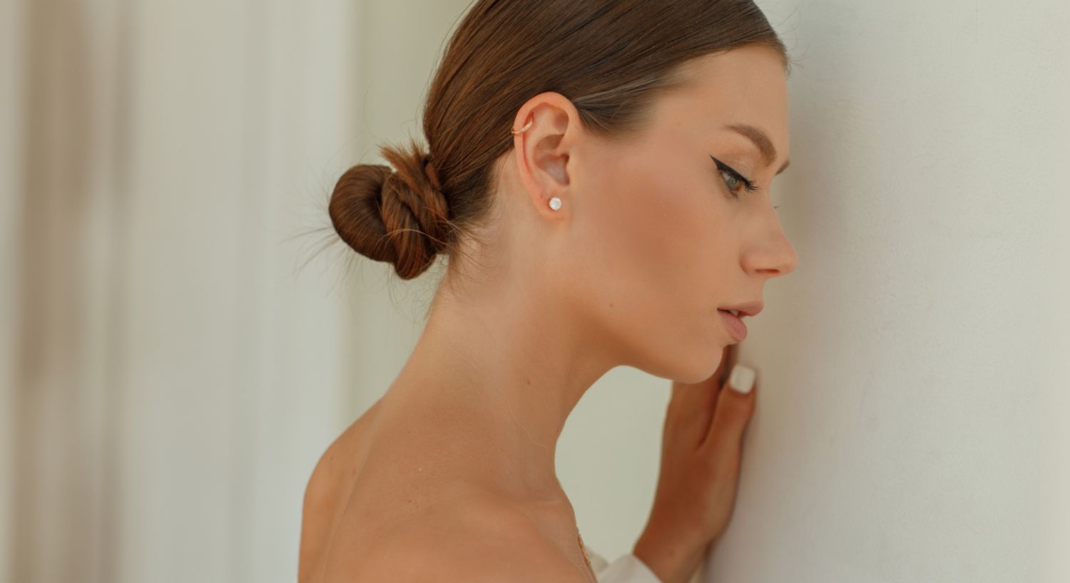 Profile of Denver Aethern model touching a white wall.