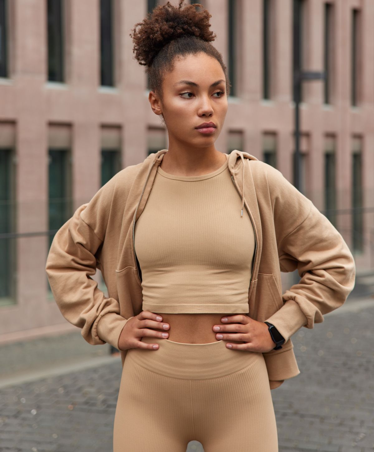 Denver tummy tuck model in black lace lingerie sitting on bed.