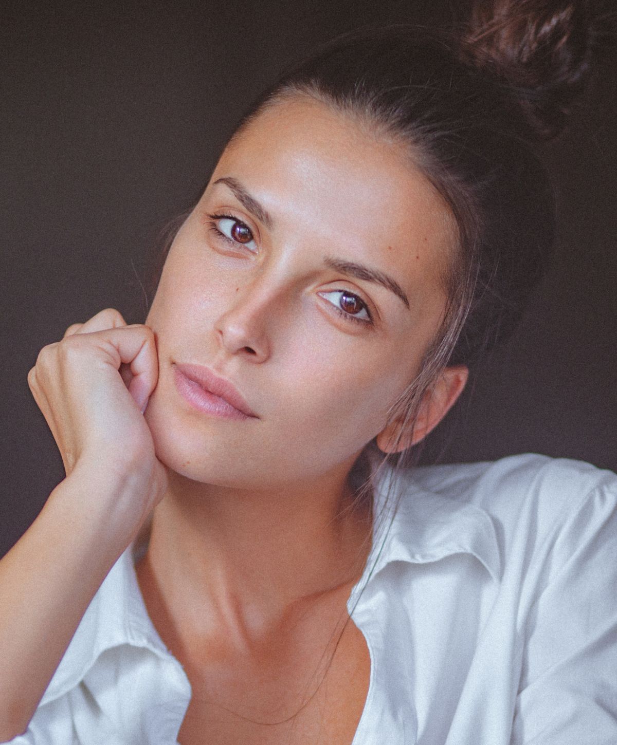 Woman in a white shirt resting her chin.