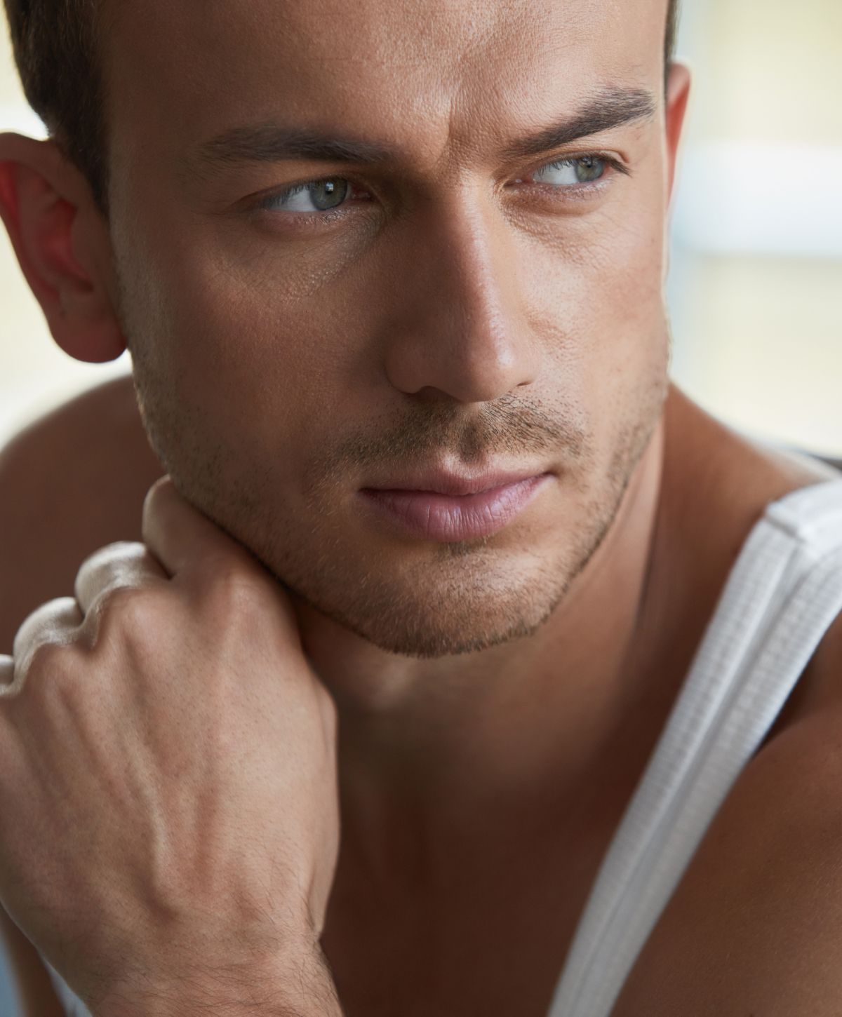 Man in tank top, thoughtful expression, close-up.