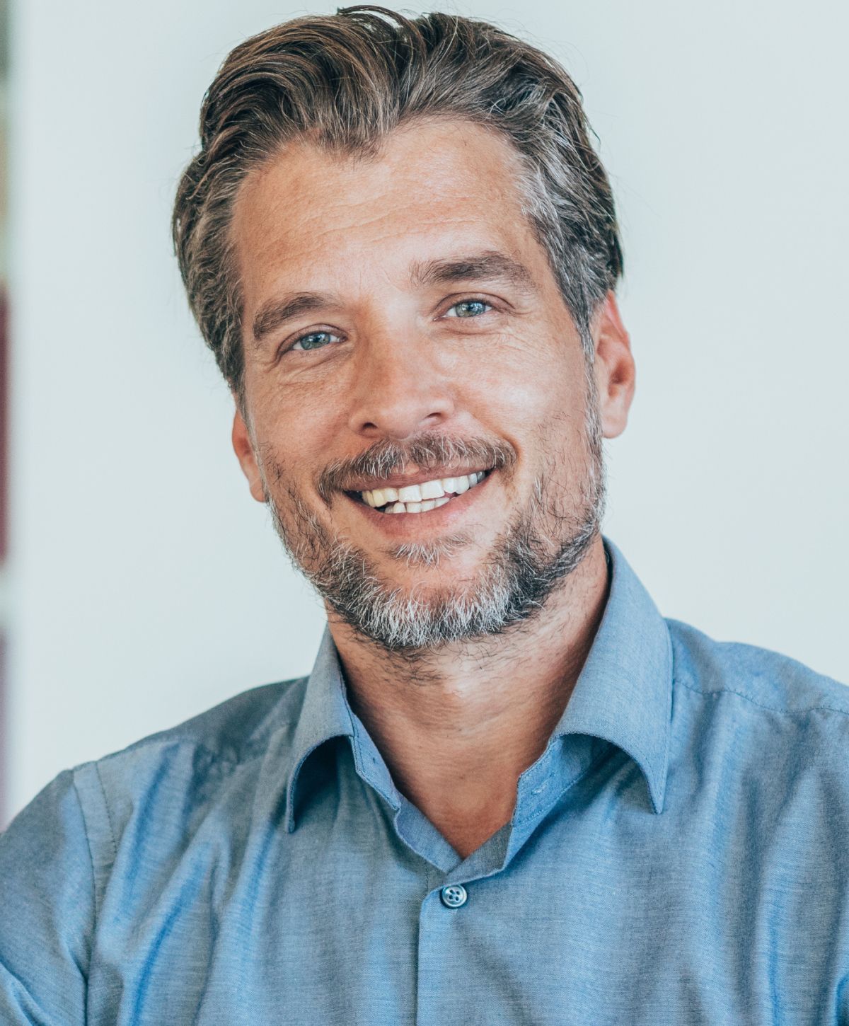 Smiling man with gray hair in blue shirt.