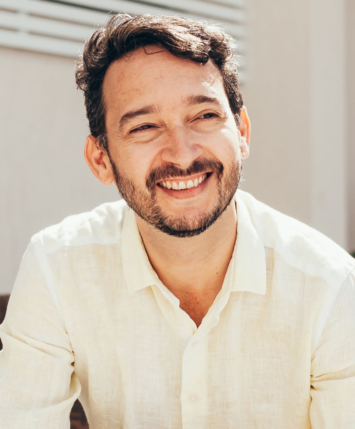 Smiling man in a light-colored shirt outdoors.