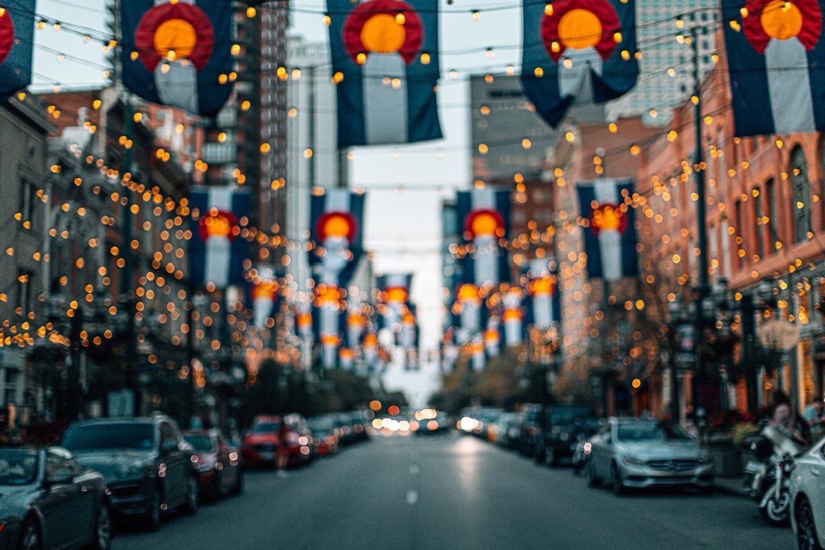 Street adorned with Colorado flags and string lights.