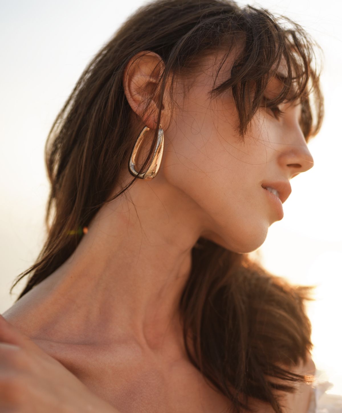 Woman wearing stylish earrings in soft lighting.