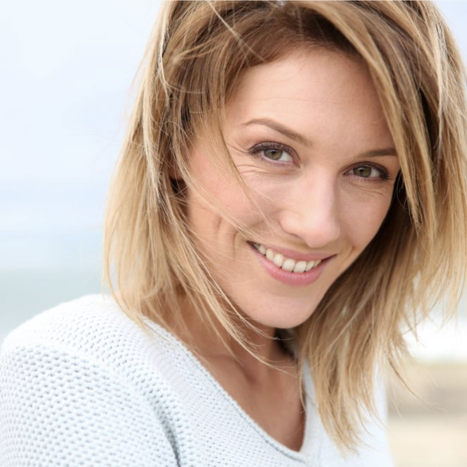 Smiling woman with wavy hair outdoors.