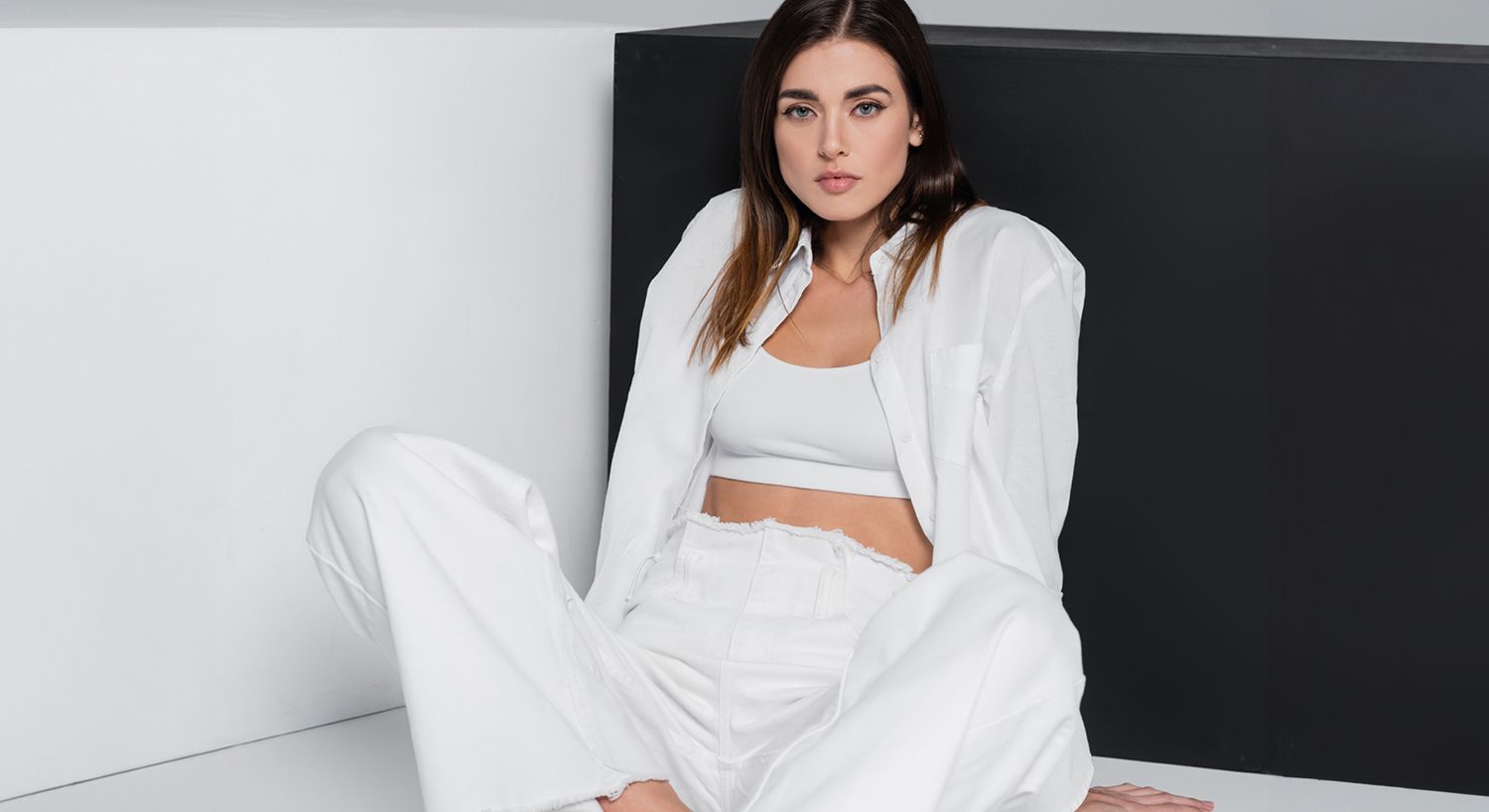 Denver umbilical reshaping model in stylish all-white outfit against minimal backdrop.