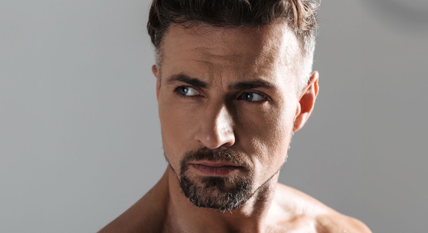 Close-up of a Denver male eyelid surgery model with intense expression.