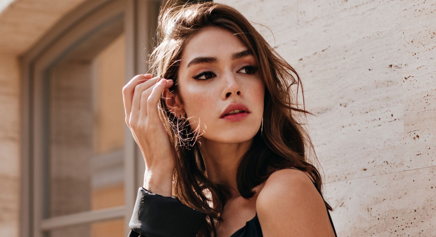 Denver dermaplaning model with flowing hair against a textured background.