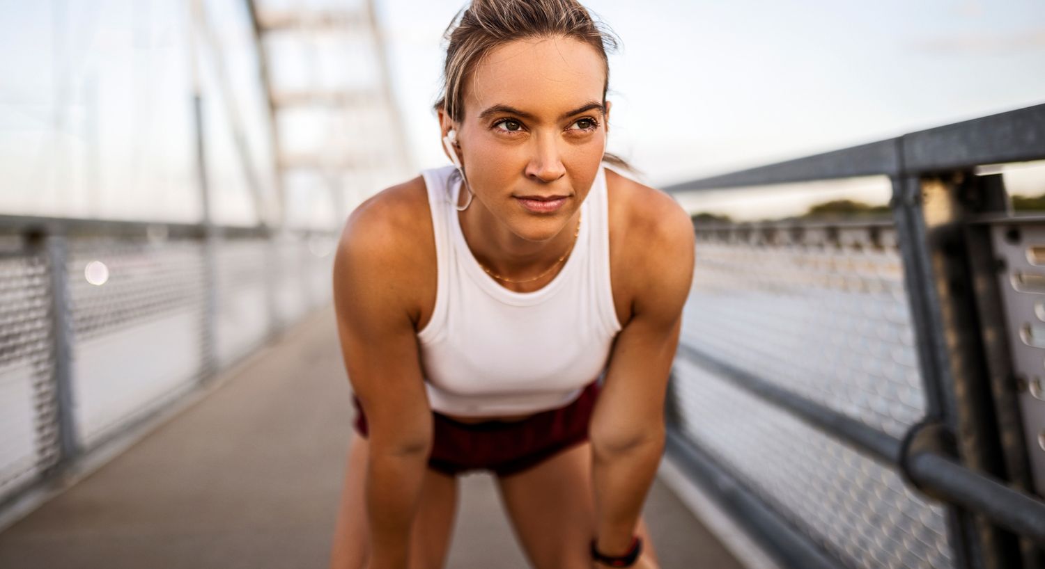 Athletic Denver medical weight loss model catching her breath on a bridge.